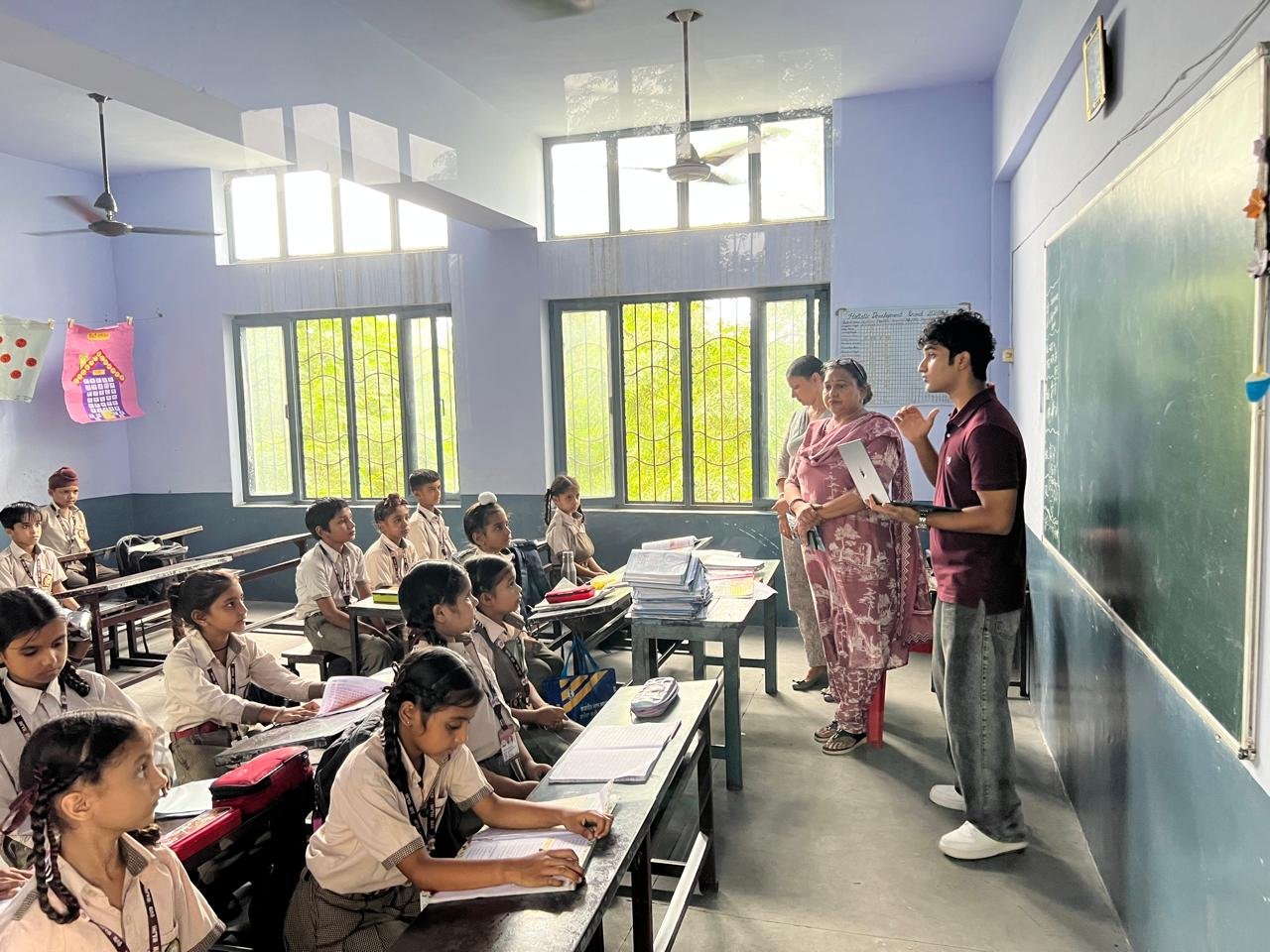 Speaking with teachers at the chalkboard as students work at their desks