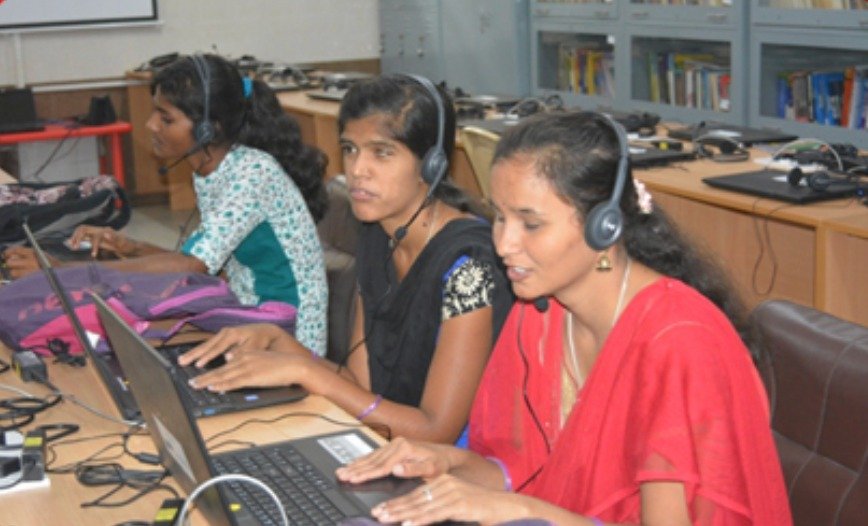 Volunteers wearing headsets and recording audio material on laptops at the library
